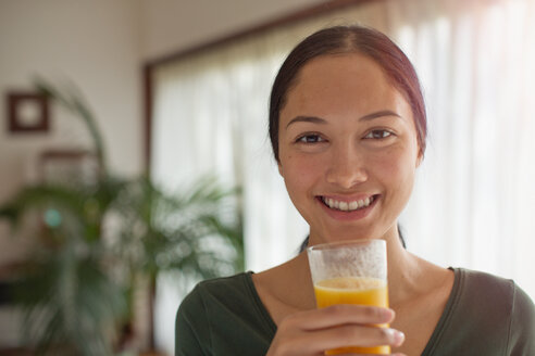 Porträt einer selbstbewussten jungen Frau, die Orangensaft trinkt - HOXF04418
