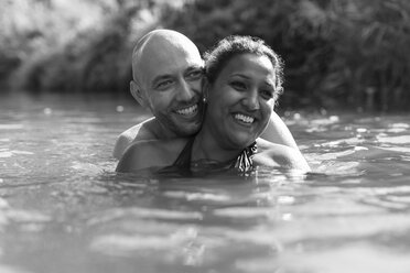 Glückliches Paar beim Schwimmen im Fluss - CAIF23048