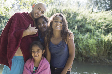 Porträt einer glücklichen Familie am sonnigen Flussufer - CAIF23051