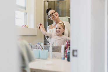 Lächelnde Mutter und Tochter im Badezimmerspiegel - CAIF23053
