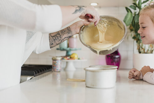 Tochter beobachtet Mutter mit Tattoos beim Backen in der Küche - CAIF23055