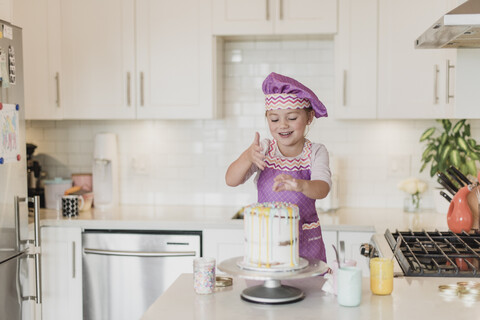Lächelndes Mädchen dekoriert Kuchen in der Küche, lizenzfreies Stockfoto