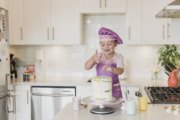 Lächelndes Mädchen dekoriert Kuchen in der Küche - CAIF23057