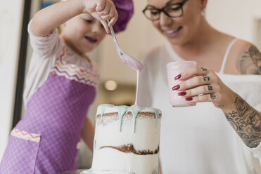 Mother and daughter decorating cake - CAIF23062