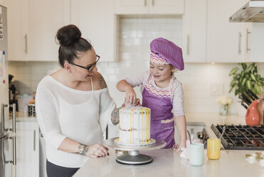 Mutter und Tochter dekorieren Kuchen in der Küche - CAIF23064