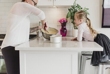 Neugieriges Mädchen beobachtet Mutter beim Backen in der Küche - CAIF23066