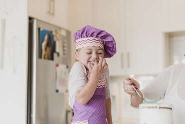 Glückliches, süßes Mädchen mit Kochmütze beim Backen in der Küche - CAIF23067