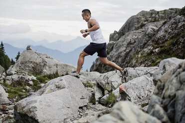 Man hiking, jumping across rocks, Dog Mountain, BC, Canada - CAIF23072