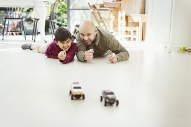 Vater und Sohn spielen mit Spielzeugautos auf dem Boden - CAIF23112