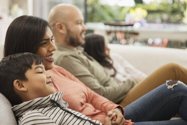 Family watching TV on living room sofa - CAIF23116