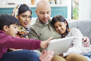 Familie benutzt digitales Tablet auf dem Sofa - CAIF23118