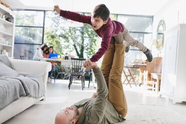 Father and son playing on living room floor - CAIF23124