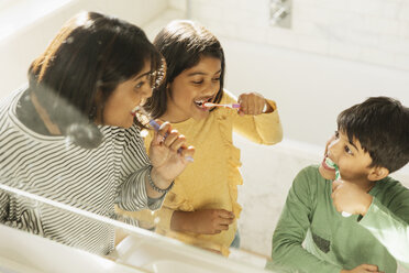Mother and children brushing teeth in bathroom - CAIF23131