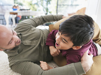 Playful father and son on floor - CAIF23147