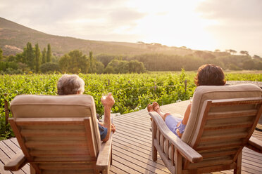 Ein Paar entspannt sich und trinkt Wein auf der sonnigen, idyllischen Terrasse eines Ferienortes - CAIF23170