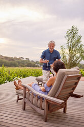 Älteres Paar entspannt sich, stößt mit Champagnerflöten auf der Terrasse des Resorts an - CAIF23189