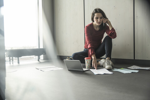 Geschäftsfrau bei der Arbeit auf dem Boden im Büro, lizenzfreies Stockfoto