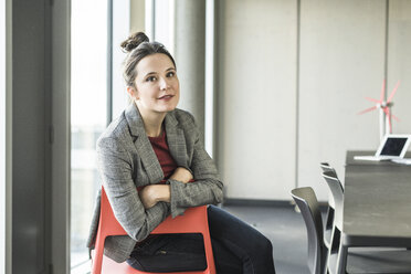 Portrait of smiling businesswoman sitting on chair in office - UUF17100