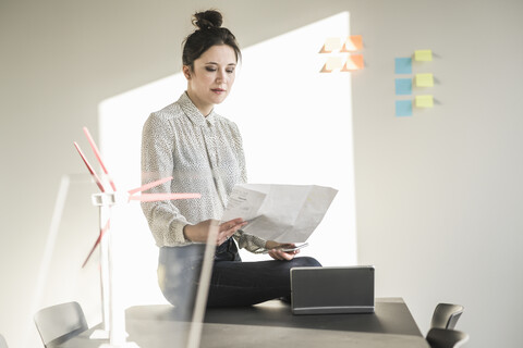 Businesswoman in office reading plan with wind turbine models on desk stock photo