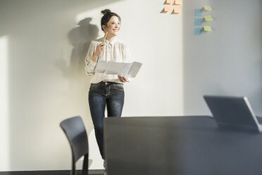 Smiling businesswoman holding plan in office - UUF17117