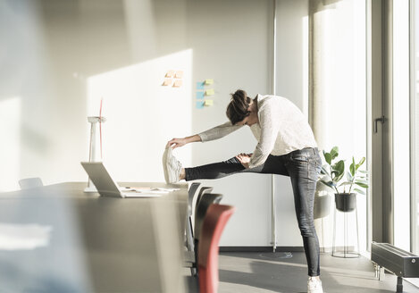 Businesswoman stretching in office - UUF17120