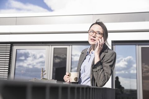 Businesswoman on cell phone on roof terrace stock photo