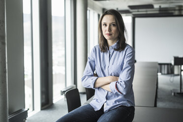 Portrait of serious businesswoman sitting on conference table in office - UUF17157