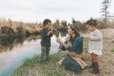 Maother and children playing with a grass blade at a river - CMSF00050