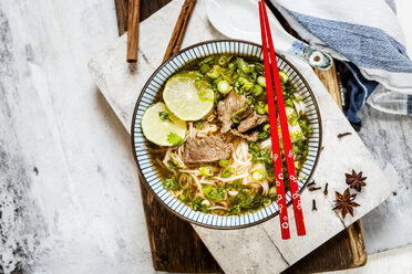 Bowl of Vietnamese Pho with rice noodles, mung beans, cilantro, spring onions and limes - SBDF03938