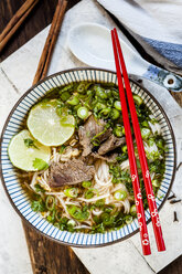 Bowl of Vietnamese Pho with rice noodles, mung beans, cilantro, spring onions and limes - SBDF03939