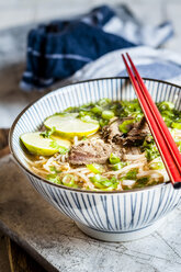 Bowl of Vietnamese Pho with rice noodles, mung beans, cilantro, spring onions and limes - SBDF03940