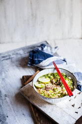 Bowl of Vietnamese Pho with rice noodles, mung beans, cilantro, spring onions and limes - SBDF03941