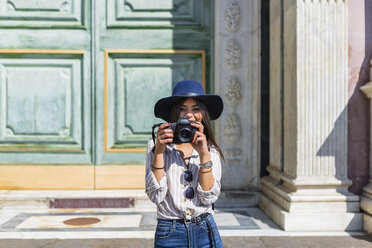 Italien, Florenz, Porträt eines lächelnden jungen Touristen, der mit einer Kamera fotografiert - MGIF00335