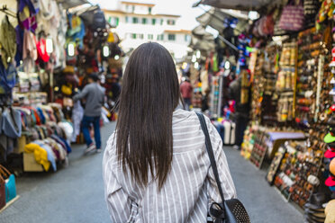 Italien, Florenz, Rückenansicht eines jungen Touristen auf dem Straßenmarkt - MGIF00343