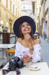 Italien, Florenz, Porträt eines glücklichen jungen Touristen, der in einem Straßencafé Espresso trinkt - MGIF00357