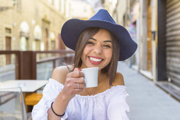 Italien, Florenz, Porträt eines glücklichen jungen Touristen, der in einem Straßencafé Espresso trinkt - MGIF00358