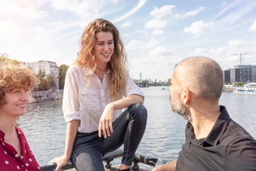 Man and female friends talking, river in background, Berlin, Germany - CUF49954