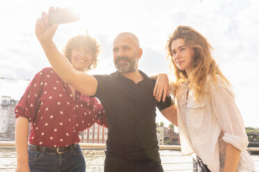 Mann und Freundinnen machen Selfie mit Smartphone auf Brücke - CUF49961