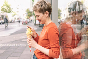 Woman eating ice cream in front of shop, Cologne, Nordrhein-Westfalen, Germany - CUF49994
