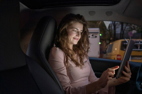 Junge Frau benutzt digitales Tablet im Auto - CUF49998