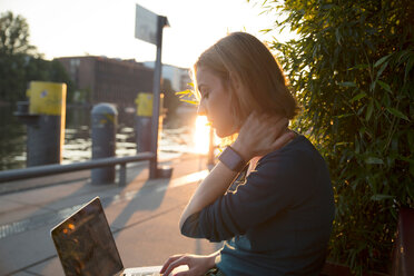 Junge Frau mit Laptop vor einem Café, Berlin, Deutschland - CUF50005
