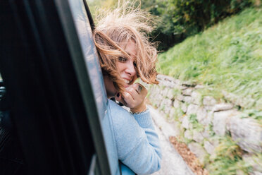 Woman turning around out of car window - CUF50057