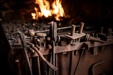 Reihe von Werkzeugen vor dem Feuer in einer Schmiedewerkstatt, lizenzfreies Stockfoto