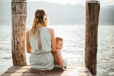 Mother and toddler son sitting on pier, rear view, Lake Orta, Piemonte, Italy - CUF50073