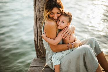 Mutter und kleiner Sohn sitzen umarmend auf dem Pier, Porträt, Ortasee, Piemont, Italien - CUF50075