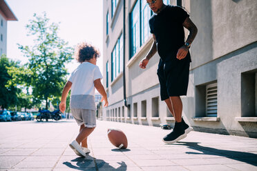 Vater und Sohn spielen mit Rugbyball auf dem Bürgersteig - CUF50100