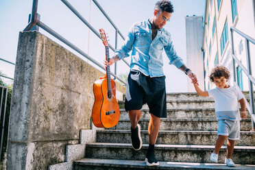 Vater trägt Gitarre und hält die Hand des Sohnes auf der Treppe - CUF50110