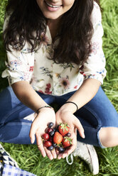 Top view of woman showing berries at a picnic in park - IGGF00994