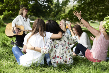 Gruppe von Frauen mit Gitarre, die sich bei einem Picknick im Park amüsieren - IGGF01003