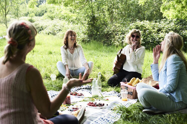 Gruppe von Frauen mit Gitarre, die sich bei einem Picknick im Park amüsieren - IGGF01006